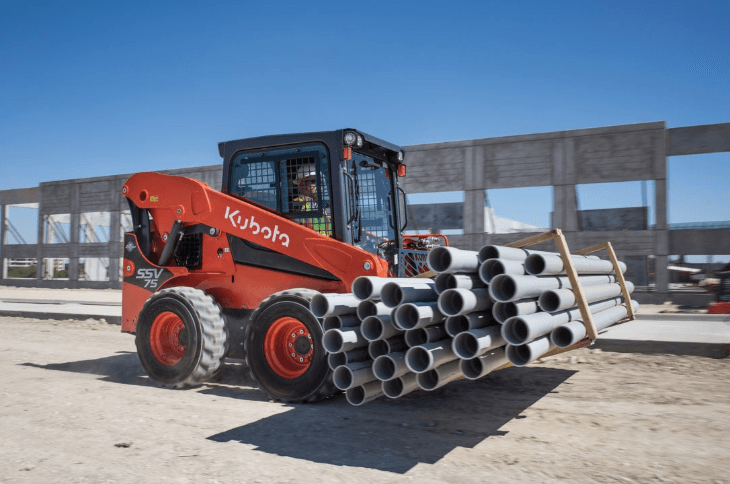 Skid steer moving a stack of pipes