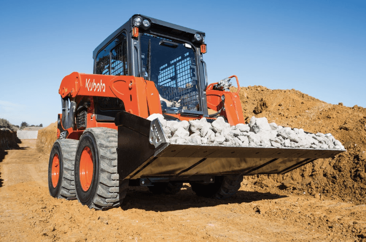 Skid steer moving a bucket full of large rocks