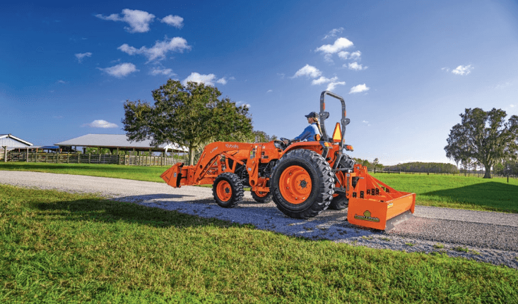 Woman using box blade to level gravel driveway