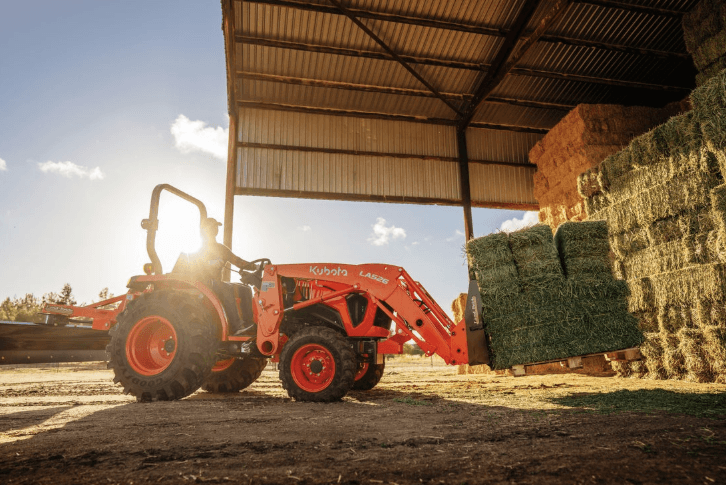 Tractor moving pallet of hay